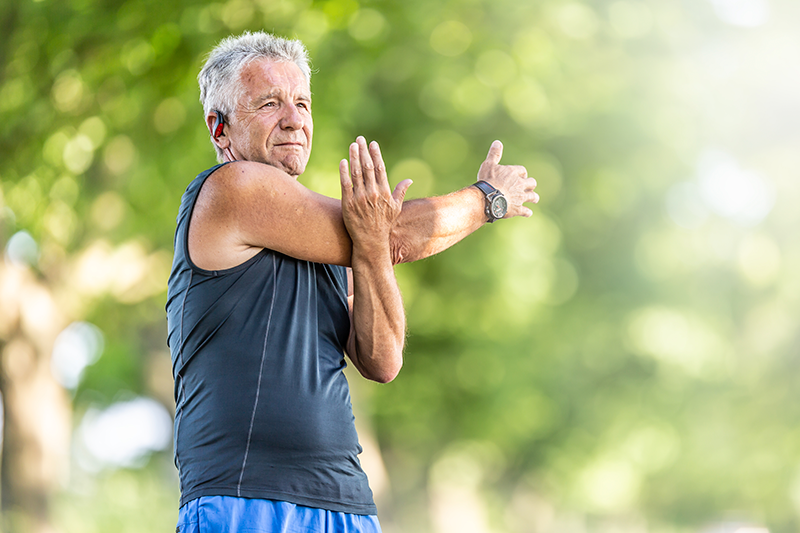 Idoso se alongando em ao ar livre.