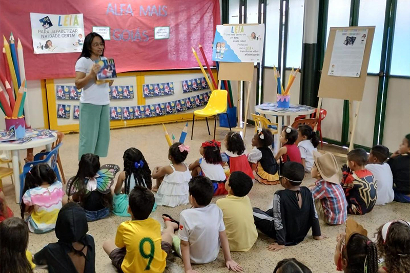 Crianças sentadas de frente com a professora.