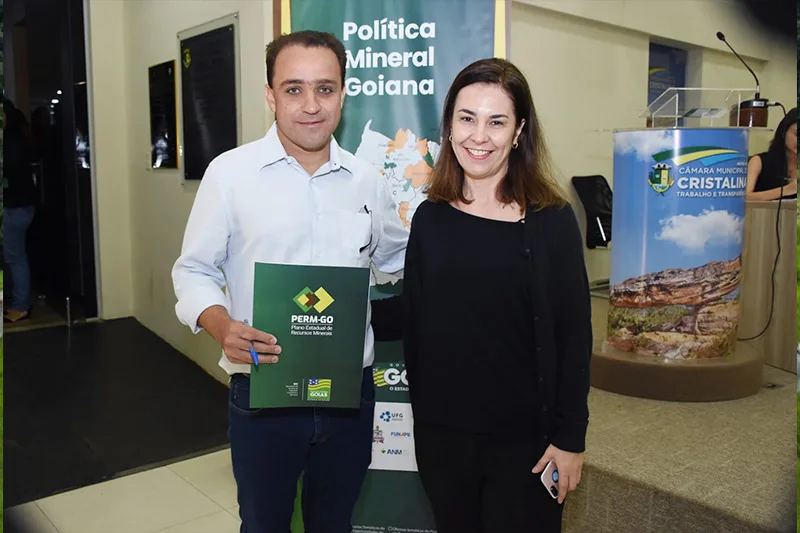 Prefeito de Cristalina segurando o livro na mão, abraçado com uma mulher.
