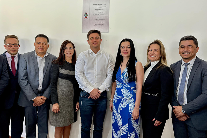 Pessoas lado a lado em frente a placa.